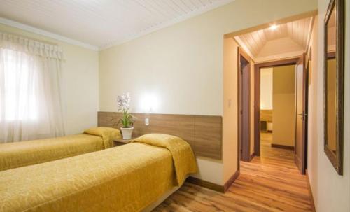 a hotel room with two beds and a hallway at Hotel Bologna in Campos do Jordão
