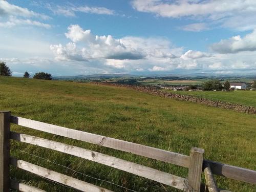 a wooden fence in the middle of a field at The Herdsman Luxury Shepherds Hut in Barnoldswick