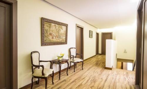 a room with two chairs and a table and a painting at Hotel Bologna in Campos do Jordão