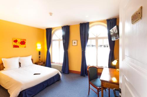 ein Hotelzimmer mit einem Bett, einem Schreibtisch und einem Fenster in der Unterkunft Hôtel Restaurant La Cigogne in Munster