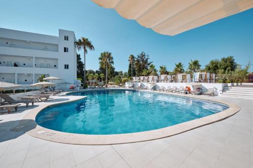 a swimming pool at a resort with tables and chairs at Hotel Ankaa - Adults Only in Porto Cristo