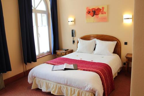 a hotel room with a bed with a book on it at Hôtel Restaurant La Cigogne in Munster