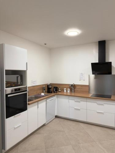 a kitchen with white cabinets and a black appliance at EXCEPTIONNEL Studio VERSAILLES in Le Chesnay
