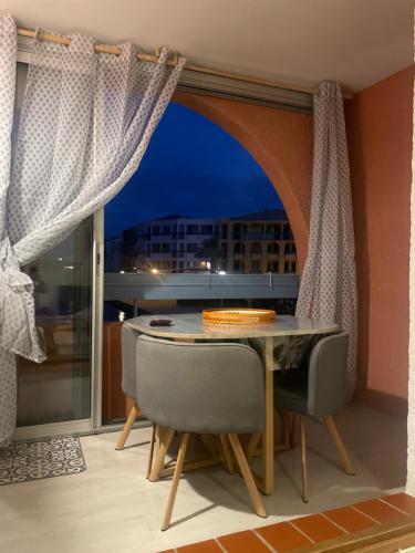a dining room with a table and chairs and a window at Appartement Marina in Le Barcarès
