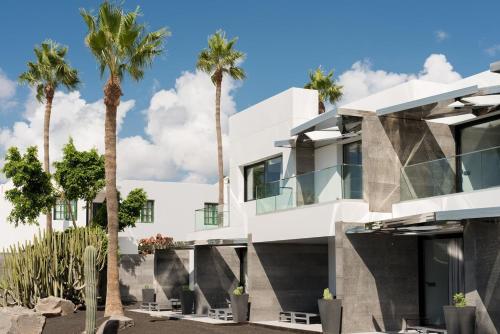 a white house with palm trees in front of it at La Isla y el Mar, Hotel Boutique in Puerto del Carmen