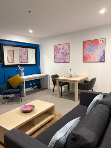 a living room with a couch and a table at Oaks Glenelg Balcony Apartment in Glenelg