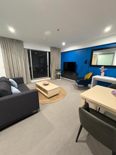 a living room with a couch and a tv at Oaks Glenelg Balcony Apartment in Glenelg