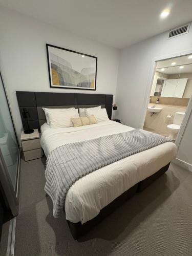 a bedroom with a large bed and a bathroom at Oaks Glenelg Balcony Apartment in Glenelg