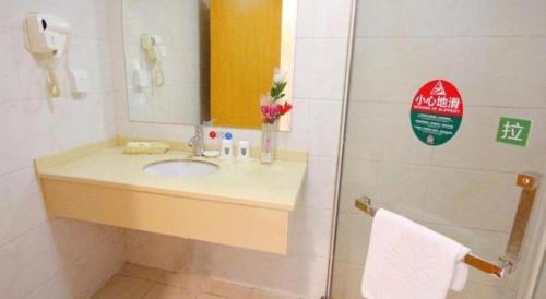 a bathroom with a sink and a mirror and a shower at GreenTree Alliance Suzhou Zhangjiagang Nanfeng Town Hotel in Zhangjiagang
