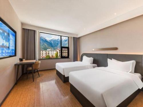 a hotel room with two beds and a flat screen tv at GreenTree Inn Tibet Nyingchi City Biji Shenshan in Nyingchi