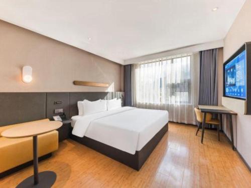 a hotel room with a large bed and a television at GreenTree Inn Tibet Nyingchi City Biji Shenshan in Nyingchi