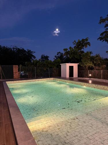 a swimming pool at night with the moon in the sky at The Outskirt Melaka in Kampong Lendu