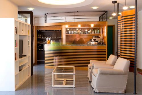 a bar with two white chairs and a counter at Aparthotel Carinzia in Lignano Sabbiadoro