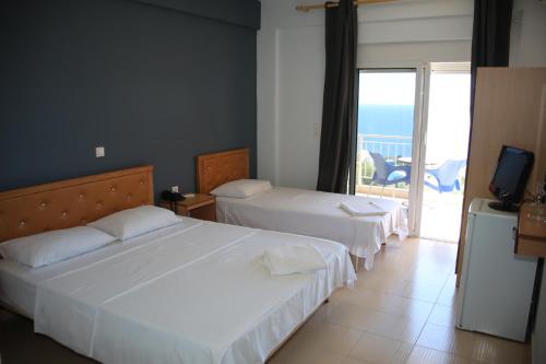 two beds in a hotel room with a balcony at La Maroja View Hotel in Dhërmi