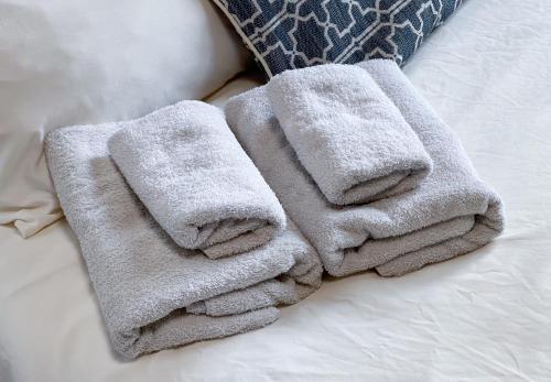 Una pila de toallas encima de una cama en ぱんだホステル岩谷, en Tokio