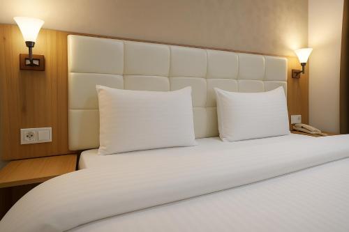 a large bed with two white pillows and a phone at Sayyoh Hotel in Tashkent