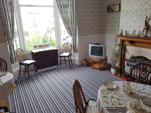 a living room with a table and a television at Brookfield Guesthouse in Cleethorpes