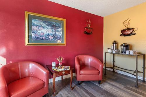 a waiting room with two red chairs and a table at Suburban Studios Albuquerque Uptown in Albuquerque