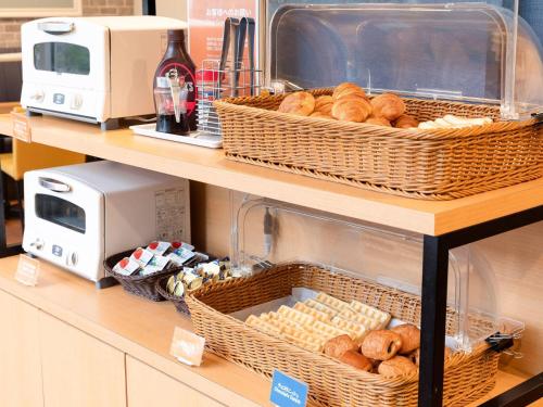 a store shelf with baskets of bread and a toaster at Comfort Hotel Narita in Narita