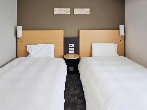 two beds sitting next to each other in a room at Comfort Hotel Hachinohe in Hachinohe