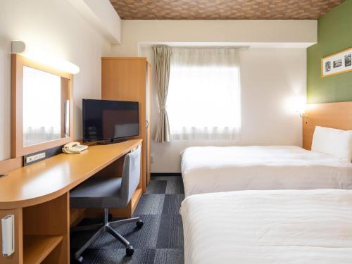 a hotel room with two beds and a desk with a computer at Comfort Hotel Kurosaki in Kitakyushu