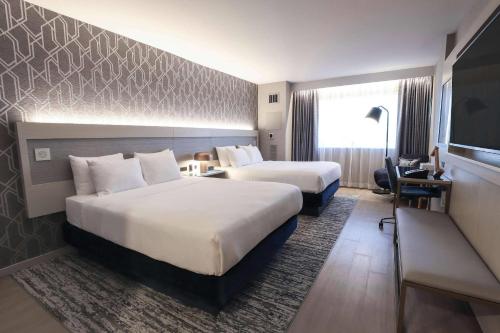 a hotel room with two beds and a desk at Radisson Plaza Hotel at Kalamazoo Center in Kalamazoo