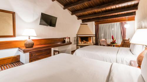 a bedroom with two beds and a fireplace at Hotel Soleil La Antigua in Antigua Guatemala