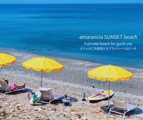a group of chairs and umbrellas on a beach at amarancia cottage hugging nature house in Minamiawaji