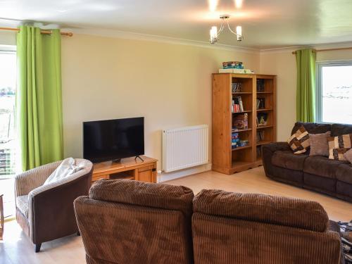 Una sala de estar con un sofá y un televisor. en Little Glengyre Farm, en Kirkcolm