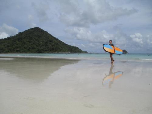 a man walking on the beach with a surfboard at Selong Belanak Bungalows in Selong Belanak