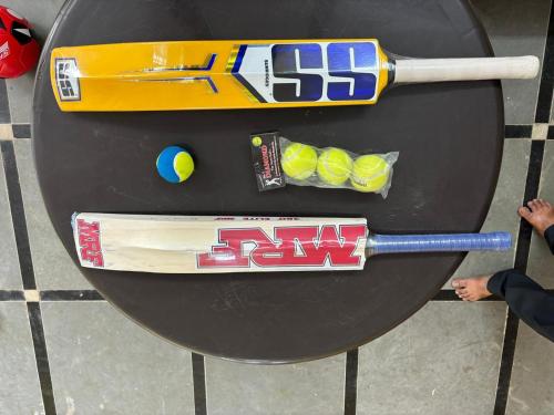 a table with a baseball bat and balls on it at Pooja Farmhouse in Hyderabad