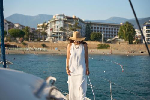 a woman in a white dress and hat standing on a boat at Hotel Grand Kaptan - Ultra All Inclusive in Alanya