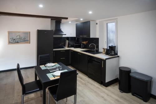 T2 Duplex Amore Chic في فيلفرانش-دي-رويرغ: مطبخ بخزائن سوداء وطاولة مع كراسي