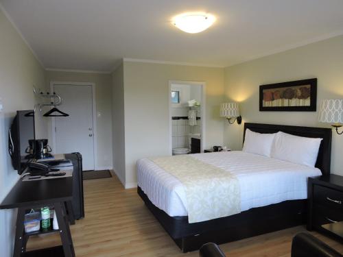 a bedroom with a bed and a desk with a phone at Almo Court Motel in Cranbrook