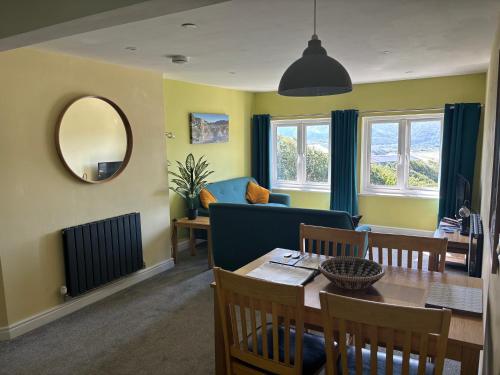 Una sala de estar con una mesa y un sofá azul. en Bryn Melyn Apartments, en Barmouth