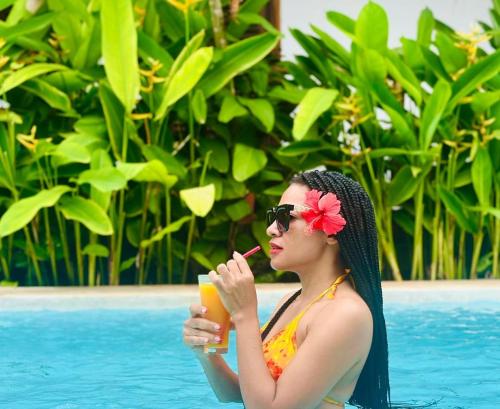 a woman in a pool smoking a cigarette and drinking a drink at Lala salama Kendwa villas in Kendwa