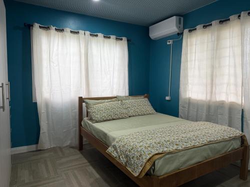 a bedroom with a bed with blue walls and curtains at Lonely Hill Apartment in Honiara