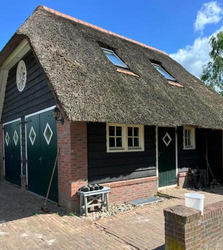 a small house with a thatched roof and a brick at De Reesterhoeve in Balkbrug