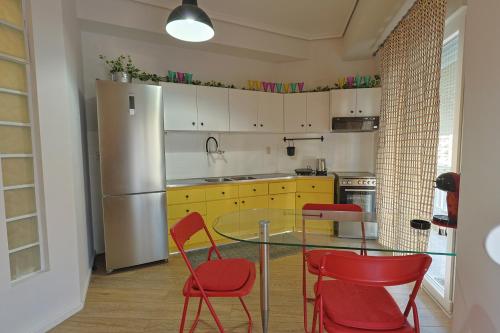 Una cocina con una mesa de cristal y sillas rojas. en Zeusplace Urban Flat, en Katerini
