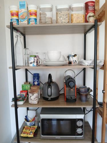 a kitchen shelf with a microwave and other kitchen items at Tinnock B&B in DʼLoughtane Cross Roads
