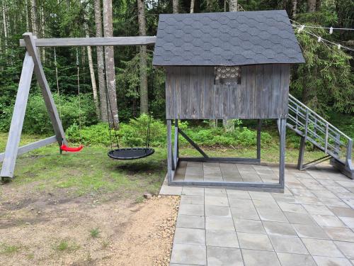 a playground with a house and a swing at Toma pirts MEŽA in Tīnūži