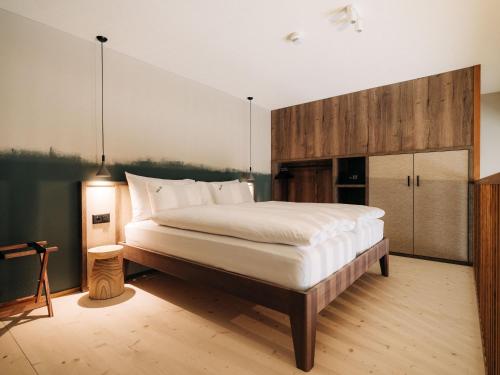 a bedroom with a large bed with white sheets at KURVE Apartments & Lounge in Adelboden