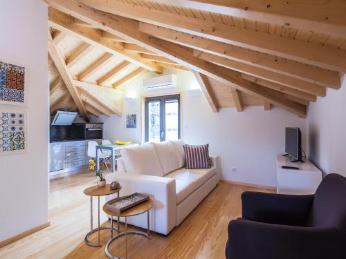 a living room with a white couch and wooden ceilings at Trindade by Guestify in Porto