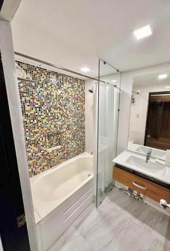 a bathroom with a shower and a tub and a sink at Kojo Hotels Premier in Tagum