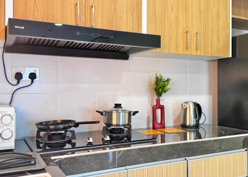 a kitchen with a stove with pots and pans at Alanis Suite With Netflix @ KLIA Sepang in Sepang