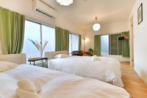 two beds in a room with green curtains at miraisya kyojima in Tokyo