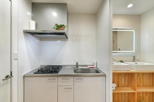 a white kitchen with a sink and a stove at miraisya kyojima in Tokyo