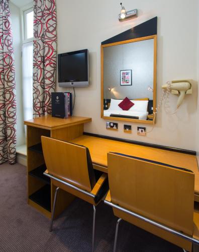 a room with a desk with chairs and a mirror at Best Western Buckingham Palace Rd in London