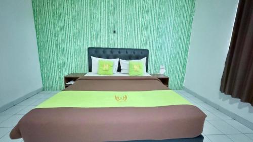 a bedroom with a large bed with yellow pillows at Hotel Huswah Airport in Jakarta