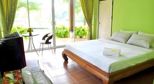 a bedroom with a bed and a television and a patio at At Home Suanphung in Ratchaburi
